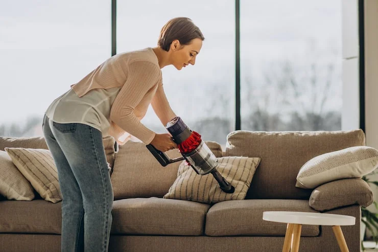 young woman with rechargeable vacuum cleaner cleaning home 1303 27167